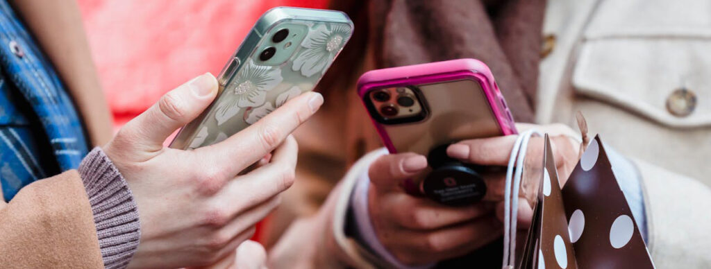 Twee mensen die samen een smartphone vasthouden, op zoek naar de beste enquêtetools voor marktonderzoek.