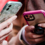 Two people holding smartphones together, looking for best survey tools for market research.
